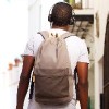 Rear view of man with backpack wearing headphones and walking