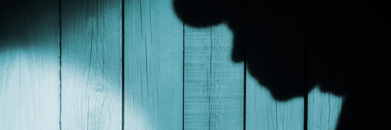 Depression at Night Feeling Like a Thief Unrecognizable burglar with flashlight in shadow on wood background, with space for text or image