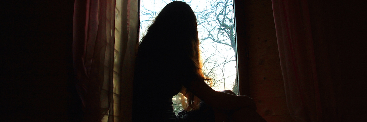 Woman sitting by the window in shadow