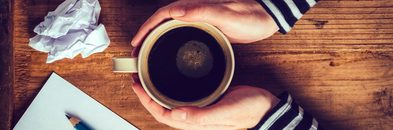 When I Wrote My First Article About My Anxiety and Depression close up on hands on coffee with a pencil and paper next to it