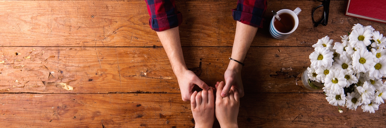 How to Talk With Your Spouse About Your Depression a couple holding hands across a table