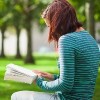 Student sitting on bench, reading on college campus