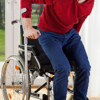 Disabled person standing up from wheelchair.