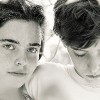 portrait of two teenagers behind some leaves