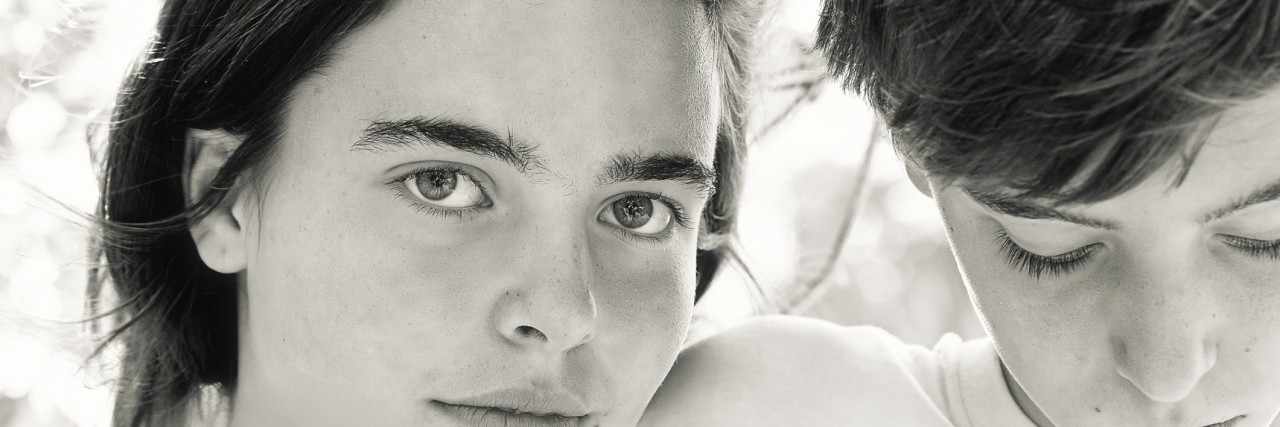 How Autism Awareness and the School System Failed My Brother and Me portrait of two teenagers behind some leaves