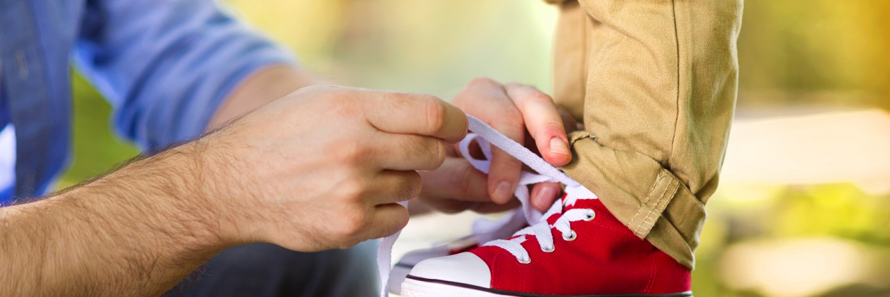 'Will My Son With Autism Ever Be a Dad?': A Mom's Response Father is helping his son to tie his shoes in summer nature