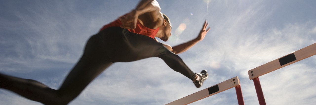 How the Olympic Hurdles Describe Life With Chronic Illness Runner jumping over running hurdle, low angle view