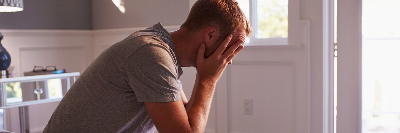 What Depression and Anxiety Tell You in Dark Moments man sitting in his pajamas with his head in his hands