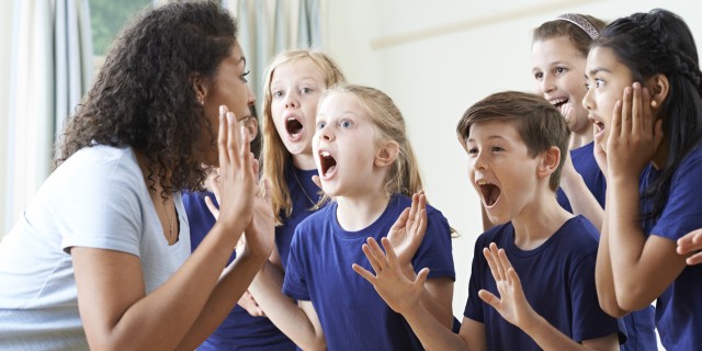 Group Of Children With Teacher Enjoying Drama Class Together