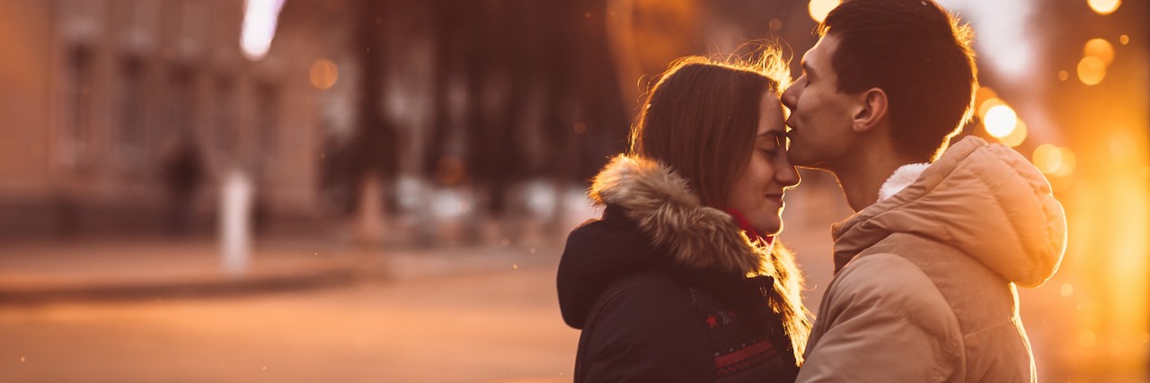 What Helps Me When My Anxiety Starts to Affect My Relationships Man hugging woman on street on a rainy night, kissing her forehead