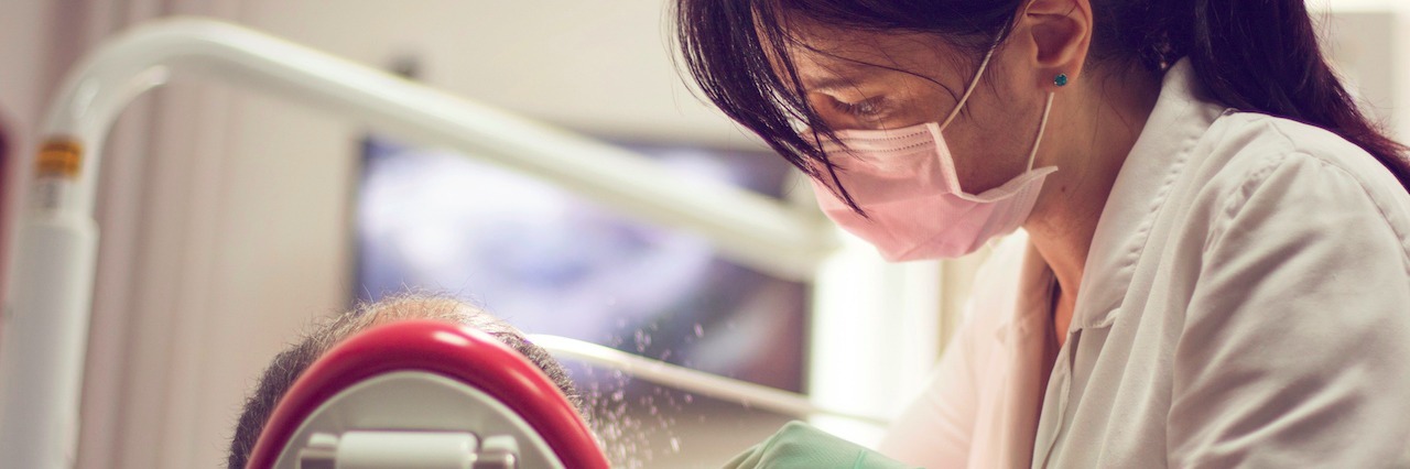 Going to Routine Doctor's Appointments With Chronic Illness Dentist examines the teeth of patient, rear view