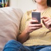 Woman on couch at home typing on a smartphone