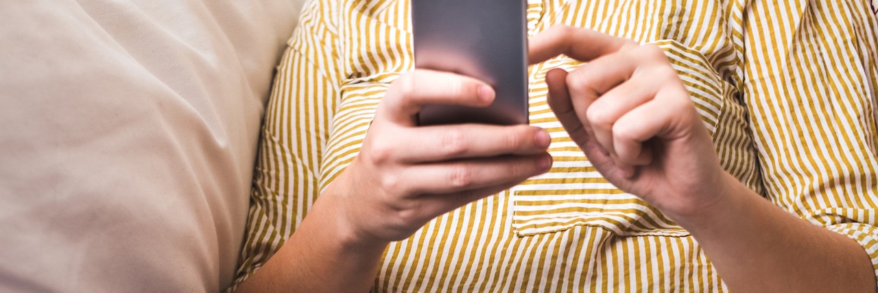 Making Summer Vacation Plans When You Have a Chronic Illness Woman on couch at home typing on a smartphone