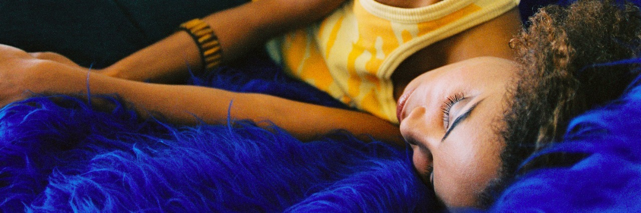 How to Practice Self-Care With Systemic Lupus a young woman sleeping on a couch