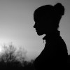 Silhouette of the girl in the nature at summer sunset in black and white.