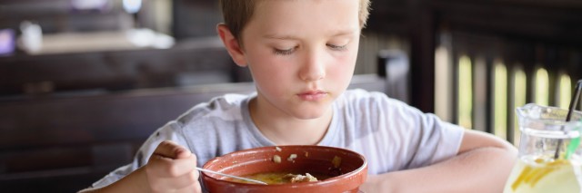 7 years old child, boy eating soup in restaurant