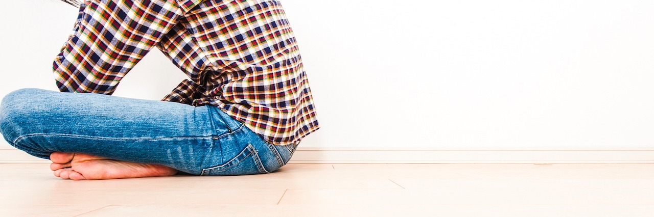 Misconceptions About Living With Depression man with his knees crossed and head down