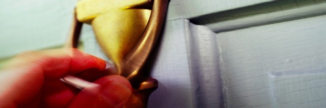 Close-up of a person's hand knocking on a door