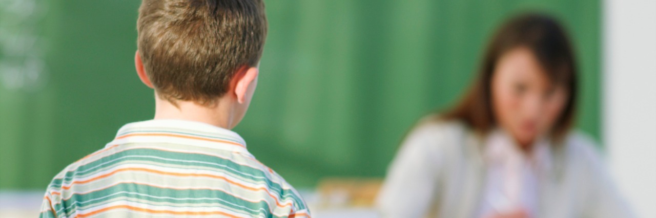 Letter to Future Teacher of My Son With Sensory Processing Disorder Student approaching teacher at her desk, working on papers