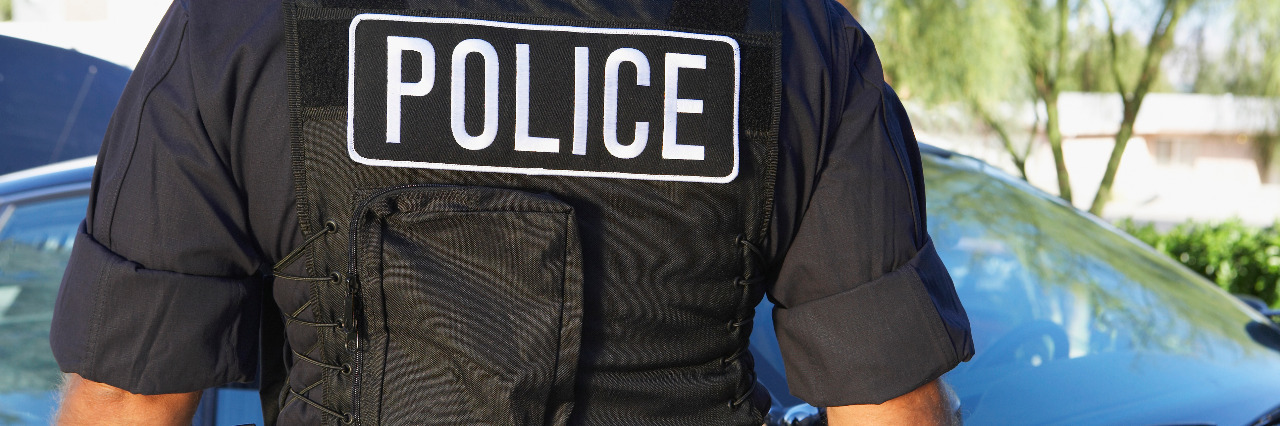 How to Stop Police Violence Against People With Disabilities Police officer in bulletproof vest, back view.