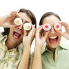 portrait of a young couple holding cupcakes up to their eyes