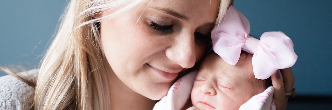 professional photo of woman with newborn baby wearing pink bow