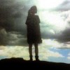 silhouette of woman standing under cloudy sky