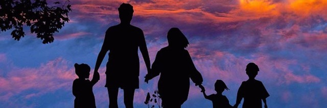 Silhouette of family against sunset sky