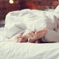 couple's feet under blanket