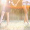 two women holding hands and walking in park