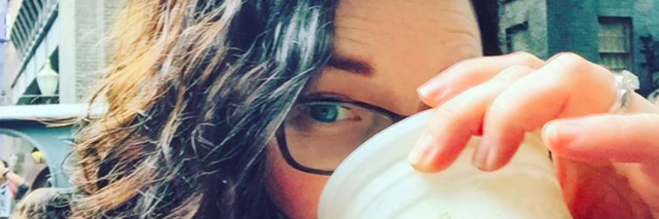Woman with dark hair and glasses drinking butterbeer