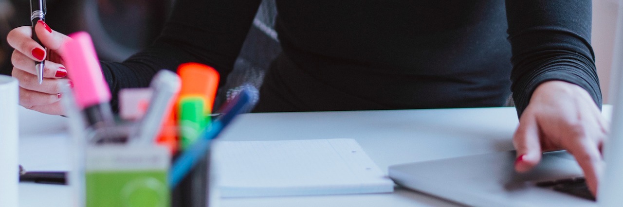 Challenges of Working With Dysautonomia and POTS Image of young woman working on laptop while sitting at her desk in modern office