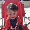 little boy with down syndrome sitting in a chair on the beach