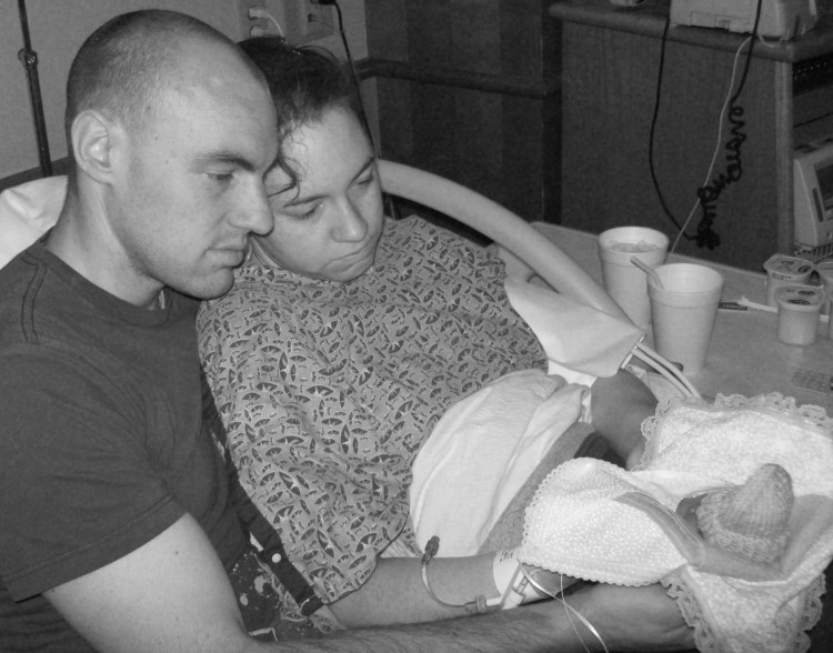 man and woman in hospital bed holding baby