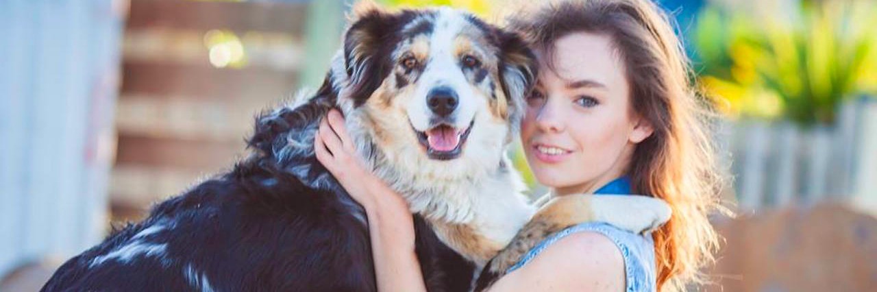 Feeling Like an Outsider Before I Got My Asperger's Syndrome Diagnosis A woman standing, holding a dog while its two paws are on her shoulders