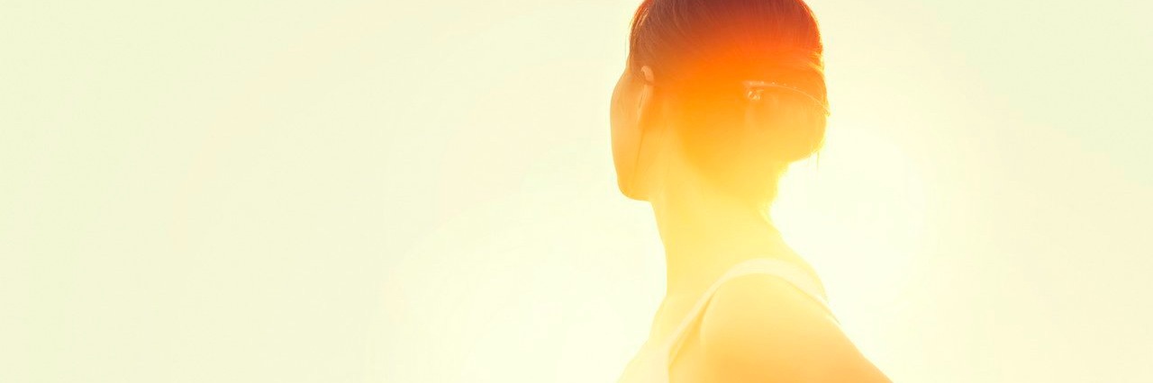 Developing a Positive Outlook After a Chronic Illness Diagnosis Young woman walking in a meadow at sunset