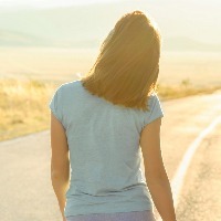 woman on road looking at the sun