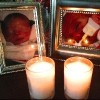 Two framed photos of babies with lit candles in front of each
