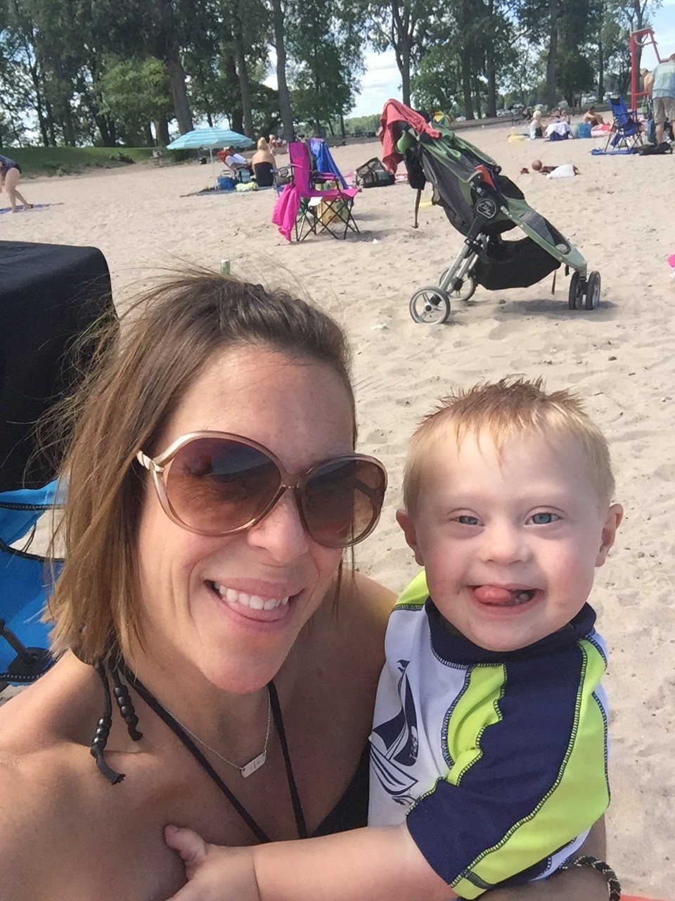 mom and little boy with down syndrome smiling at the beach