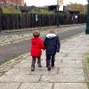 Two children walking on a sidewalk