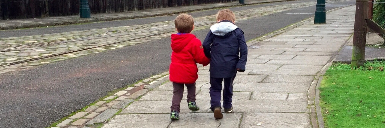 Two children walking on a sidewalk