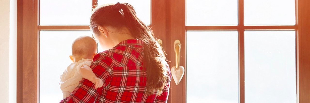 Living With an Undiagnosed Chronic Illness as a Full-Time Mom mother carrying her baby