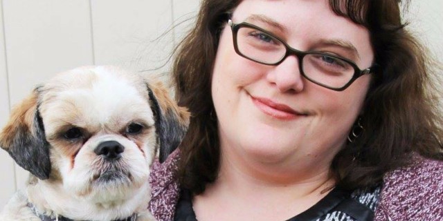 The 'Weird' Thing That Brings Me Solace When Anxiety Takes Over a woman wearing a purple sweater and glasses holding her dog