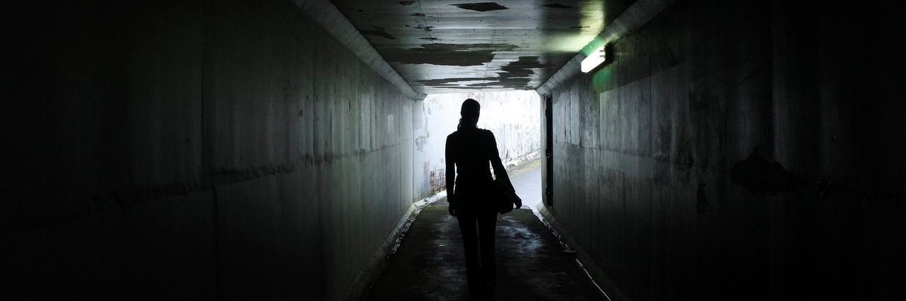 woman walking out of a dark tunnel