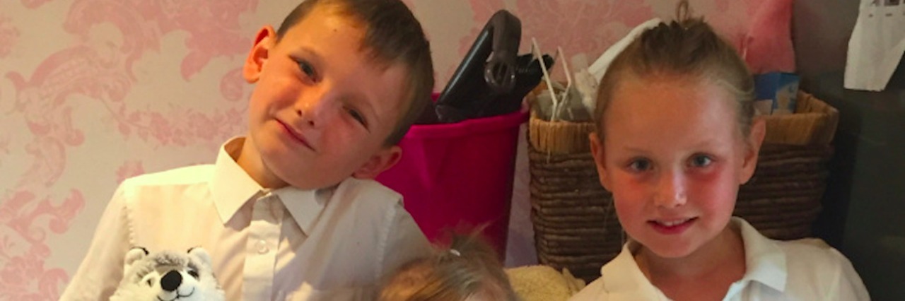 How School Uniform Rules Can Affect Kids With Special Needs Three kids wearing school uniforms, two of them holding stuffed animals