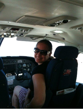 A woman in the copilot seat of a plane.
