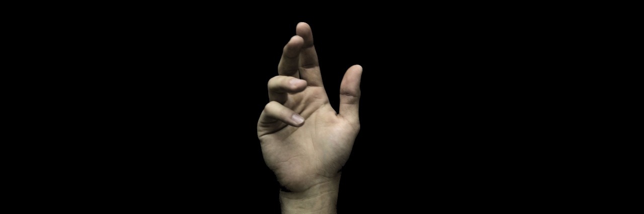 hand reaching upwards against black background