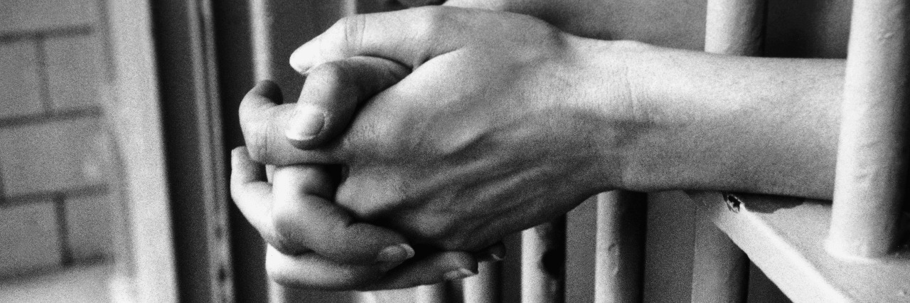 We Can't Ignore the Link Between Disability and Mass Incarceration Hands in prison cell.