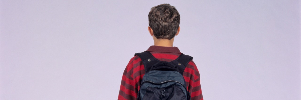 Teenage boy (14-15) with rucksack, posing in studio