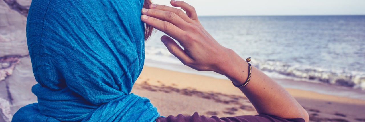 Why Not to Tell a Sick Person to There Is a 'Bigger Picture' Rear view of woman with headscarf sitting on the beach by a rock and looking at the sea